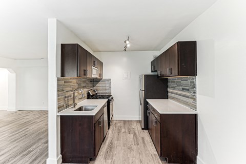 A kitchen with dark wood cabinets and a stone backsplash.